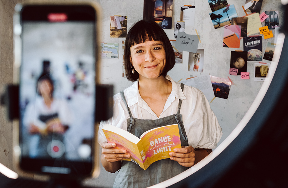 Autorin hält Buch in der hand und filmt sich mit Handykamera