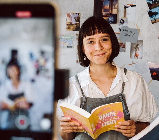 Autorin hält Buch in der hand und filmt sich mit Handykamera